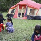 kids playing at a campsite in front of a tent