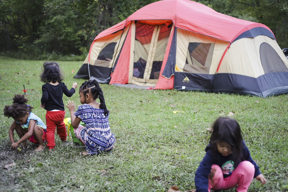 kids playing at a campsite in front of a tent