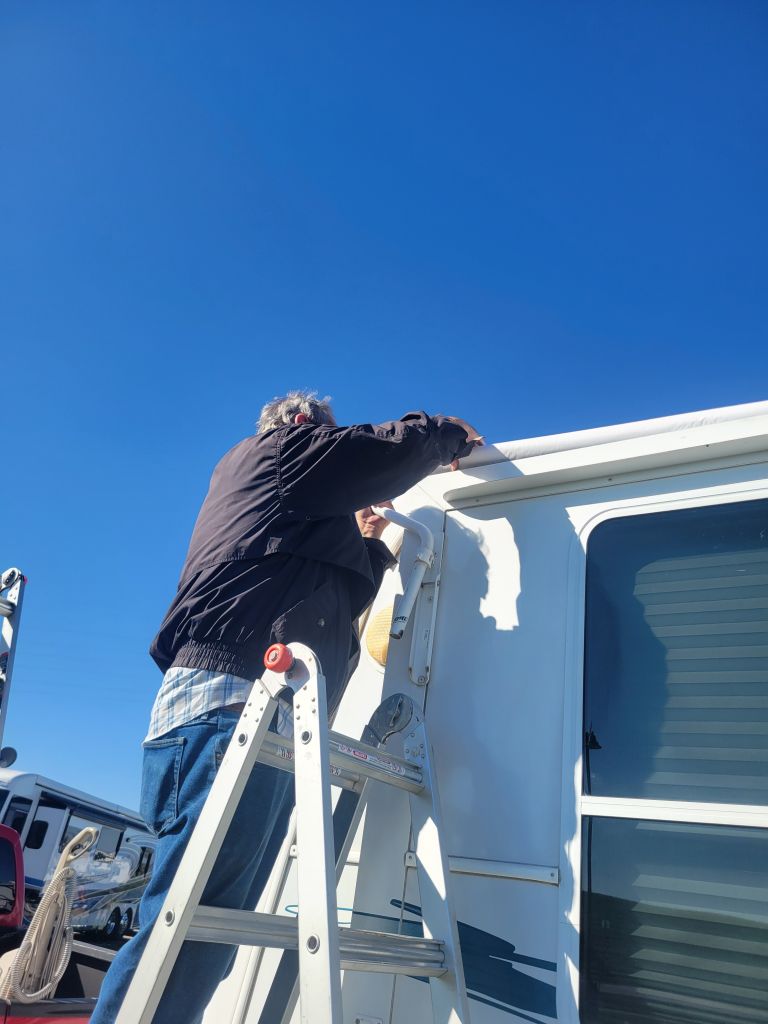 Man on a ladder fixing an RV