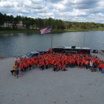 crowd in front of camper and lake